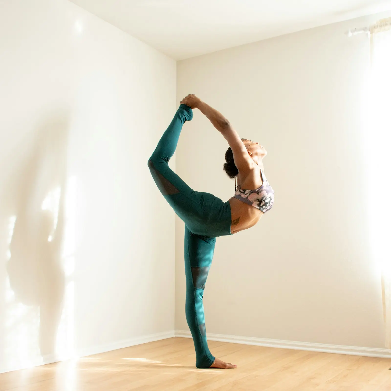 A person moving through a gentle standing pose in warm light, calm and unhurried