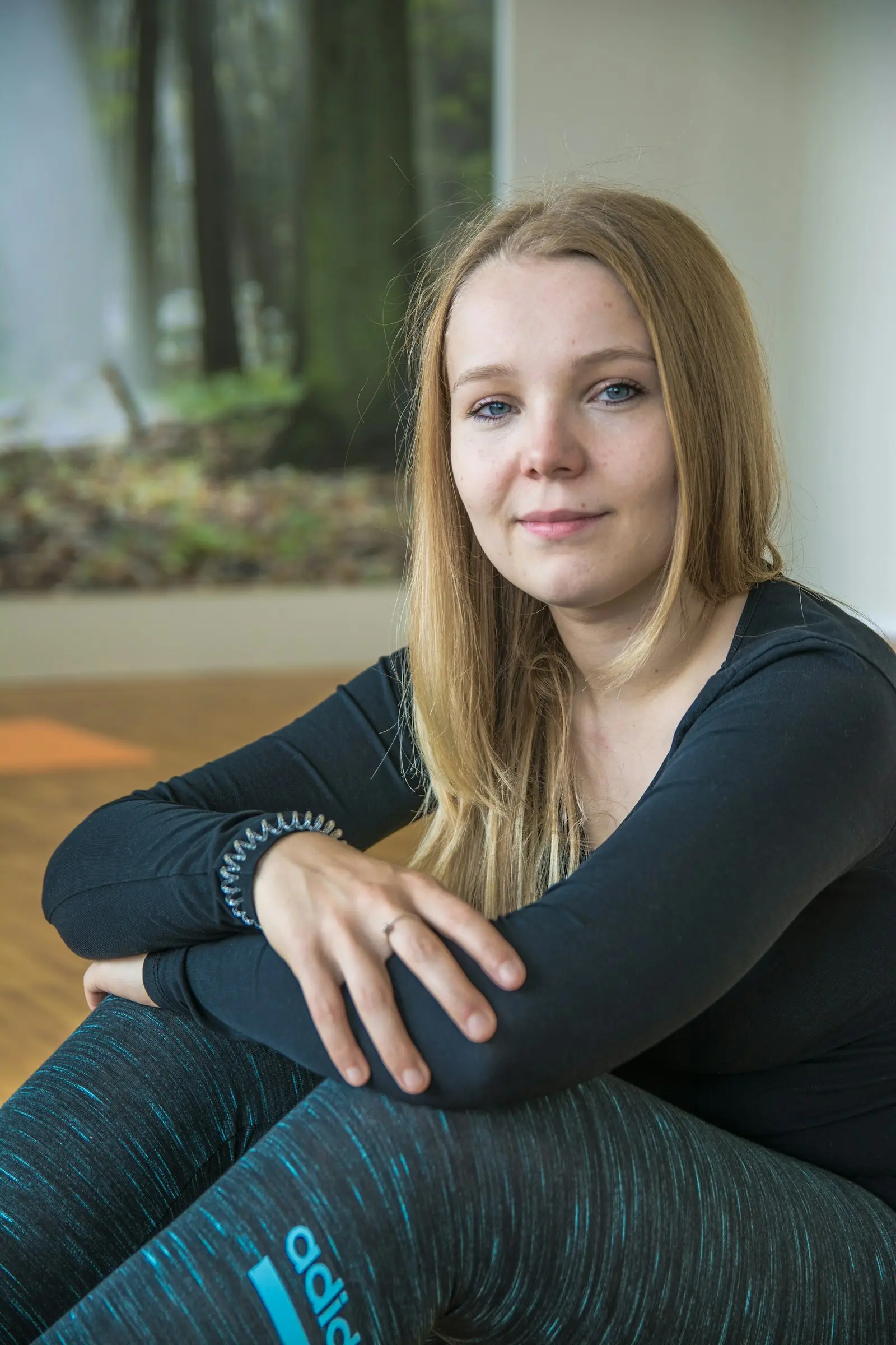 Portrait of Sofia, a woman seated on the floor in a calm pose, gentle and grounded
